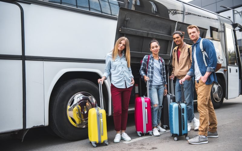 multicultural-friends-with-travels-bags-posing-near-travel-bus-at-street.jpg